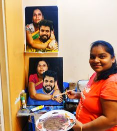 a woman standing in front of some pictures holding a plate with food on it and smiling at the camera