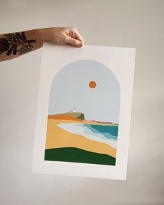 a person holding up a piece of paper with an image of a beach on it