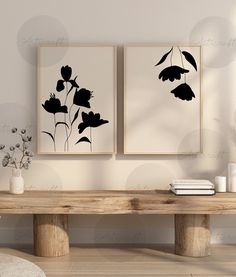 two black and white paintings on the wall above a wooden table