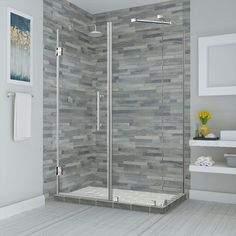 a bathroom scene with focus on the shower stall and tile wall behind it, there is a towel rack in the corner