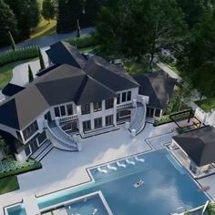 an aerial view of a large house with a pool in the foreground and several trees surrounding it