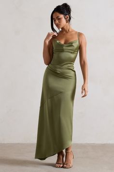 a woman in a green dress is looking down at her hair and she has one hand on her head