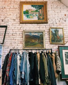 a painting hangs on the wall next to a rack with clothes hanging in front of it