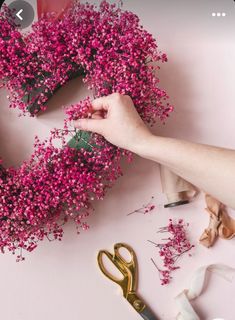 someone is making a pink flower wreath with scissors