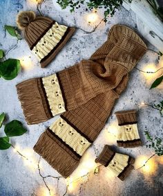 two knitted hats and mittens are laying on the ground next to some lights