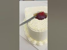 a knife is cutting into a cake with white frosting