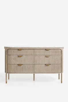 a beige dresser with gold handles and drawers on the top, against a white background