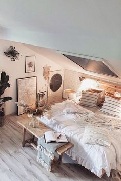 a bedroom with white walls and wood flooring is pictured in this image, there are pictures on the wall above the bed