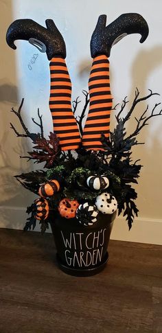 a witch planter is decorated with fake pumpkins and witches legs