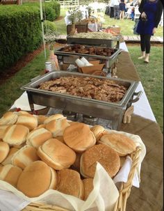 several trays of food sitting on top of a table in front of some people