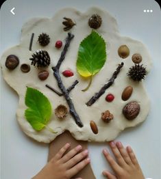 two hands touching each other over a paper plate with leaves and acorns on it