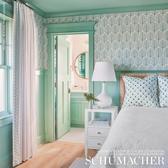 a bedroom with blue and white wallpaper, green door and bed in the foreground