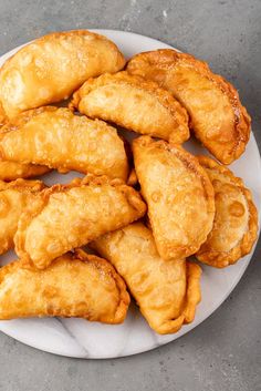 some fried food is on a white plate and sits on a gray table top next to a cup of coffee