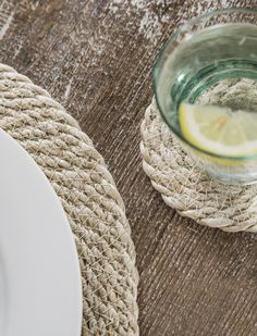 a plate with a lemon slice on it next to some burlap placemats