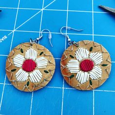 the earrings are made out of paper and decorated with red, white and green beads