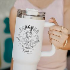 a woman holding a white coffee mug in her right hand and the words teacher written on it