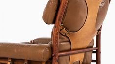 a brown leather reclining chair with wooden arms and foot rests on a white background