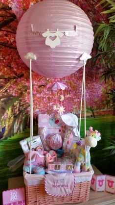 a pink basket filled with lots of baby items on top of a table next to a wall