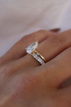 a woman's hand with a diamond ring on top of her finger and an engagement band