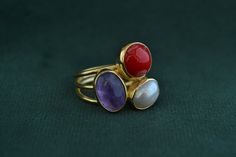 A multi-stone ring that is made with solid Sterling Silver (925 Silver). The outer layer is gold plated with 22K Gold, and the 3 stones decorating the ring are Coral, Amethyst and Pearl. Elegant Stackable Rings With Natural Stones For Anniversary, Gold Amethyst Ring With Natural Stones As Gift, Gold Fusion Rings With Stones, Gold Stackable Rings With Stones For Gift, Elegant Stackable Rings With Stones As Gift, Unique Gold Multi-stone Amethyst Ring, Unique Multi-stone Gold Amethyst Ring, Pearl And Amethyst, Mens Gemstone Rings