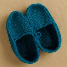 a pair of crocheted blue slippers sitting on top of a brown surface