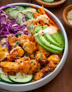 a bowl filled with chicken, cucumber and coleslaw next to two bowls of rice