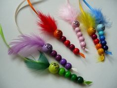 four different colored beads and feathers on a white surface