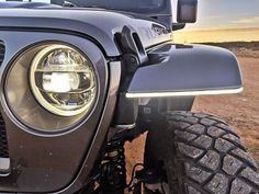 the front end of a jeep with its lights on and grill grilles off in the desert