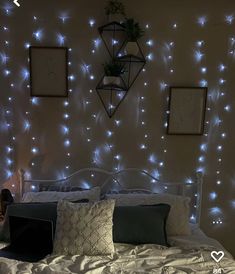 a bed room with a neatly made bed and some lights on the wall above it