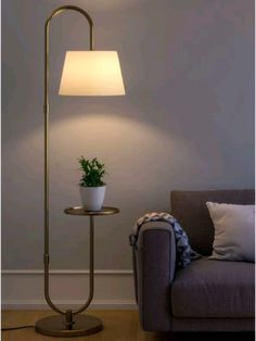 a living room with a couch, lamp and potted plant on the side table