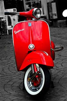 a red scooter is parked on the street