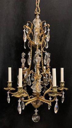 an antique chandelier with many crystal pieces hanging from it's arms and two candles on each side