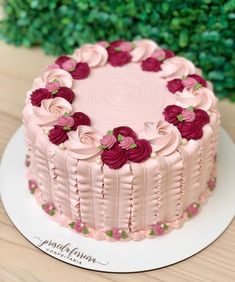 there is a pink cake with red flowers on the top and bottom, sitting on a white plate