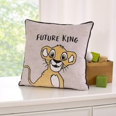 a pillow with a lion on it sitting on top of a white dresser next to a window