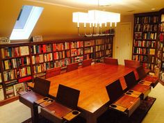 a large wooden table surrounded by chairs and bookshelves