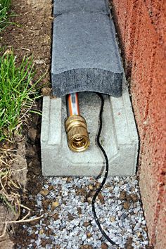 an electrical device is plugged in to a brick wall with gravel and grass around it