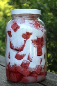 a jar filled with red and white sugar cubes on top of a wooden table