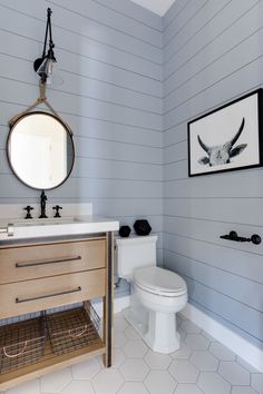 a white toilet sitting next to a bathroom sink under a mirror on top of a wooden cabinet