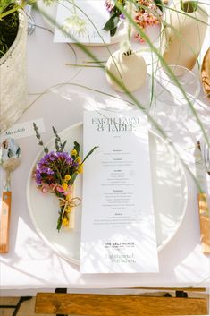 the table is set with flowers and menus for an outdoor wedding reception in california