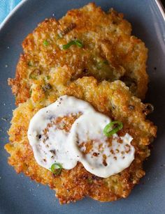 two crab cakes on a blue plate with a fork next to it and a napkin