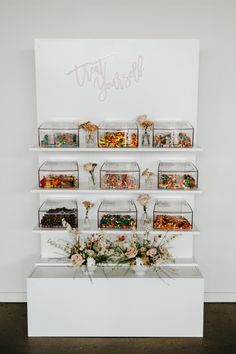 a white shelf filled with lots of different types of candies and flowers on top of it