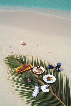 an image of food on the beach with palm leaves