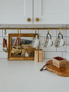 the kitchen counter is clean and ready for us to use as an art piece, with coffee mugs hanging from hooks