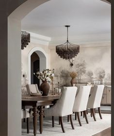 a dining room table with white chairs and a chandelier hanging from the ceiling