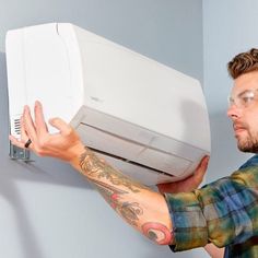 a man holding up an air conditioner in front of his face