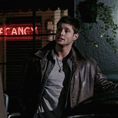 a young man standing in front of a neon sign