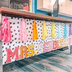 a school desk decorated with colorful tassels and polka dot paper on the wall