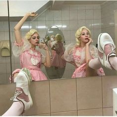 two women in pink dresses and white shoes are looking at their reflection in the mirror