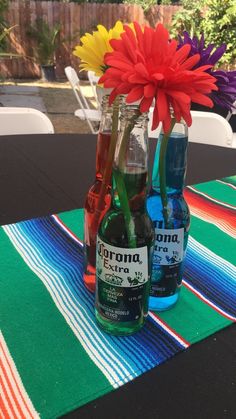 two bottles with flowers in them sitting on a table