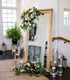 a large mirror sitting on top of a table next to vases filled with flowers